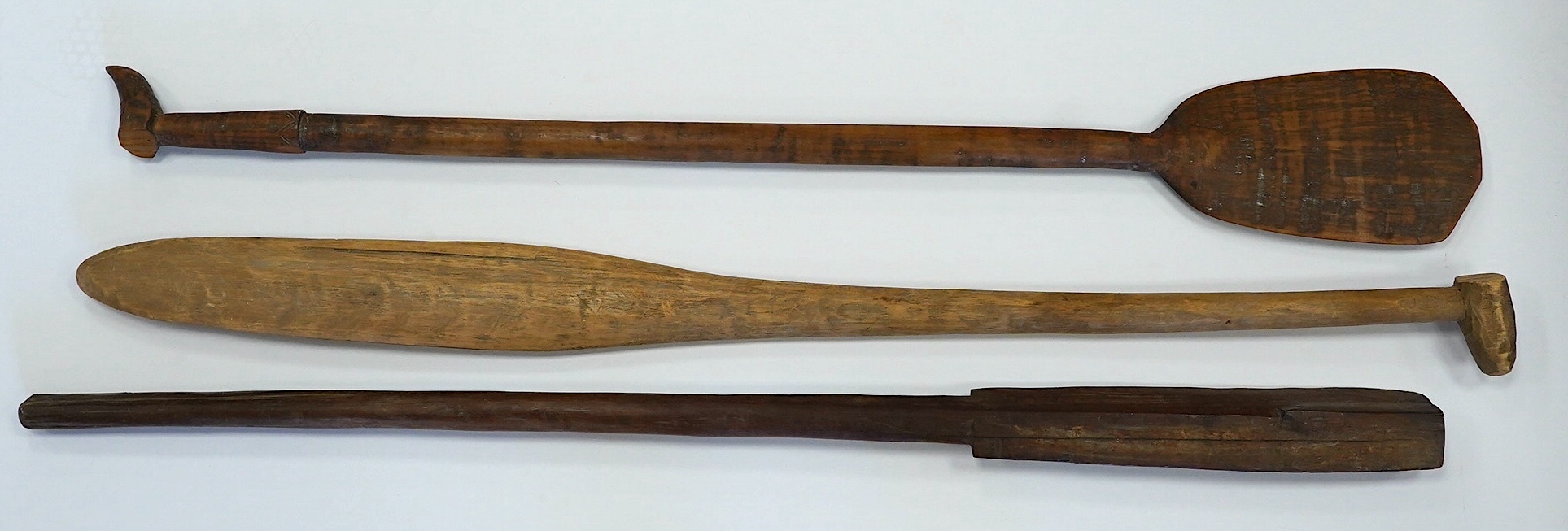 Two tribal carved wood paddles and an ironwood club, longest 104cm. Condition - poor to fair, one paddle missing part of the grip, splits to the wood, etc.